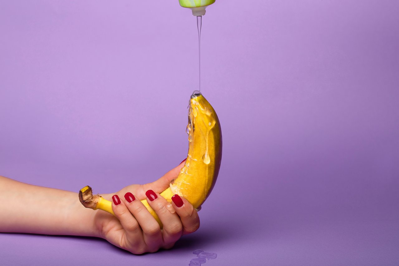 Lubricant is run over a banana held by one hand