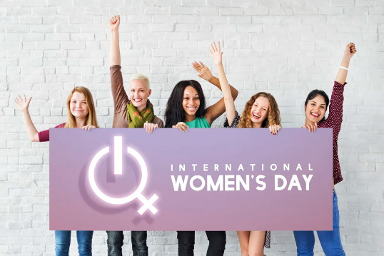 Frauen hinter einem Schild zum internationalen Frauentag 2023